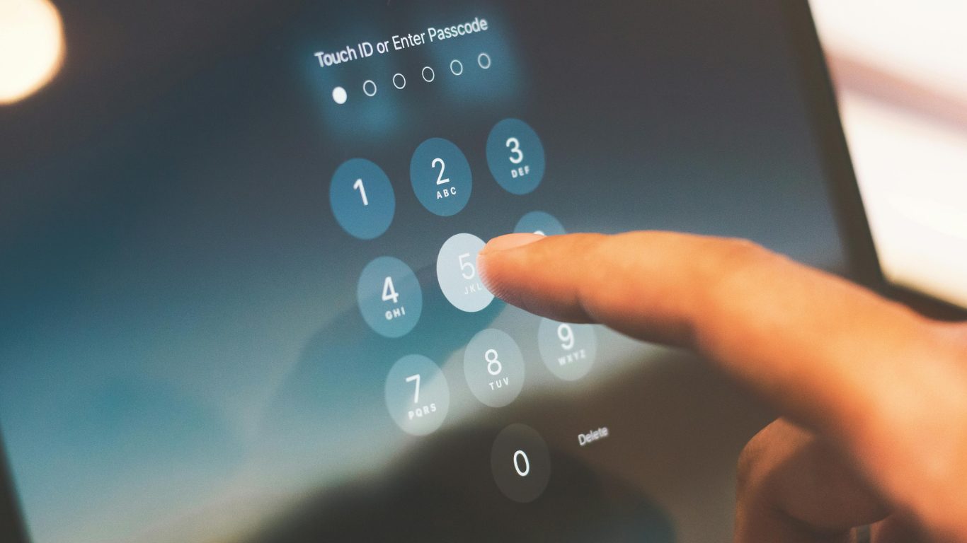 A finger entering a passcode on a phone lock screen.