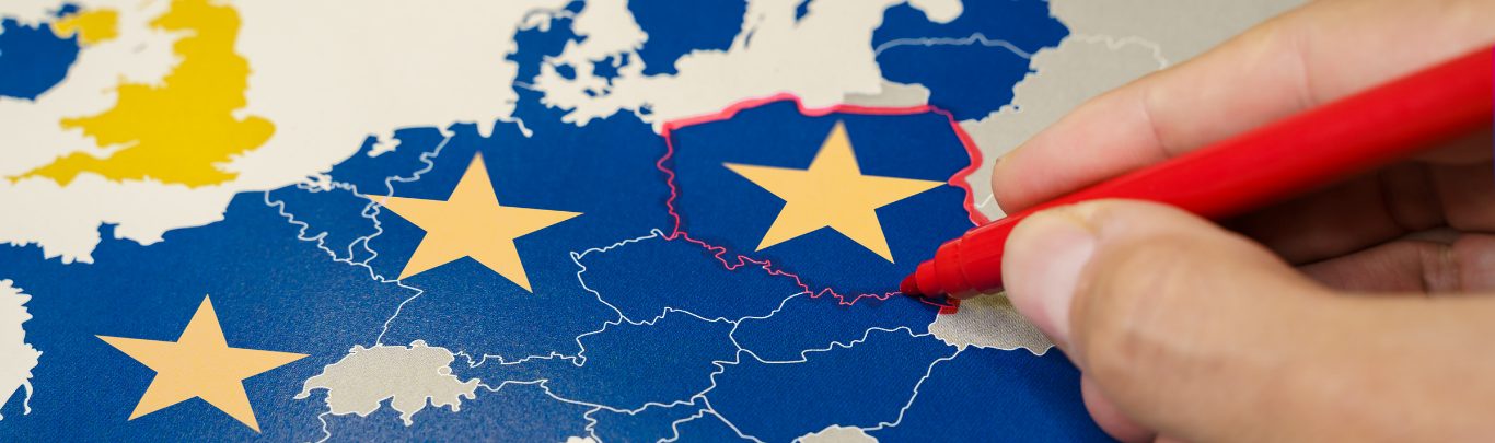 A hand outlining a country on a map of the European Union.