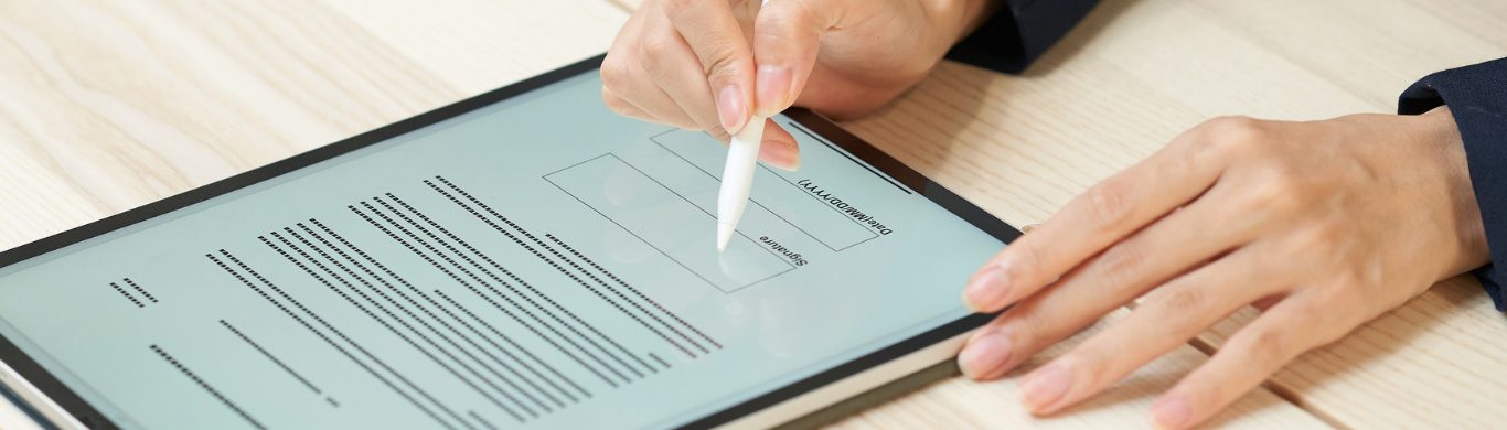 A hand signing a document on a tablet with a stylus.